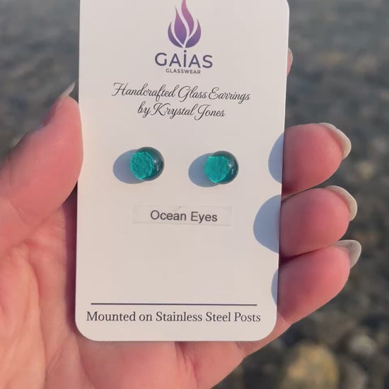 Handmade Ocean Eyes fused glass stud earrings featuring ocean-inspired blue tones and stainless steel posts, crafted by Canadian glass artist Krystal Jones.