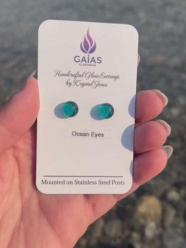 Handmade Ocean Eyes fused glass stud earrings featuring ocean-inspired blue tones and stainless steel posts, crafted by Canadian glass artist Krystal Jones.